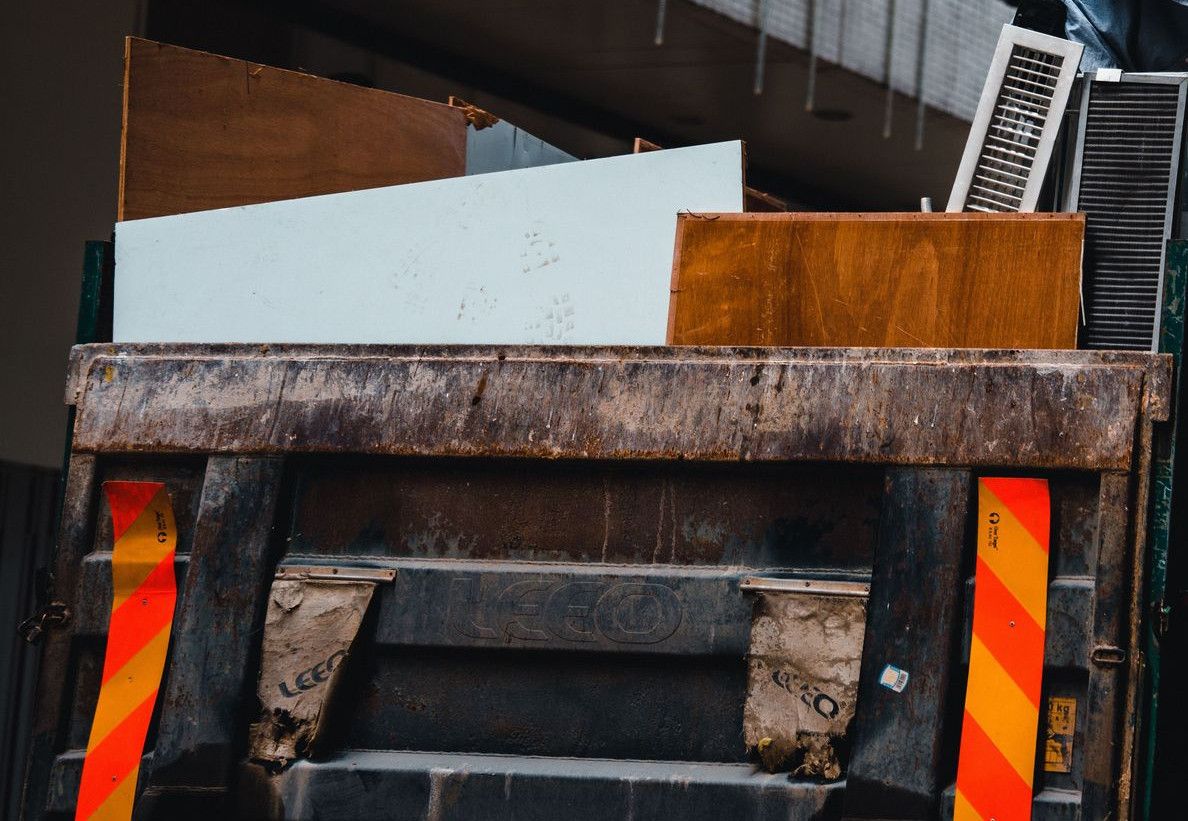 A man wearing a mask manages construction debris in a city environment from a large truck.